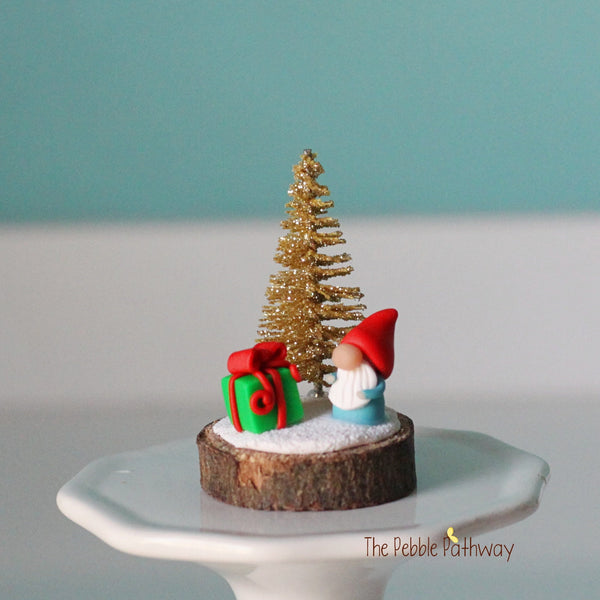 Micro mini gnome with tiny present and gold glitter Christmas tree on wood slice - ThePebblePathway